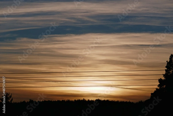 Fototapeta power lines, trees and sunset and orange sky in tyrol