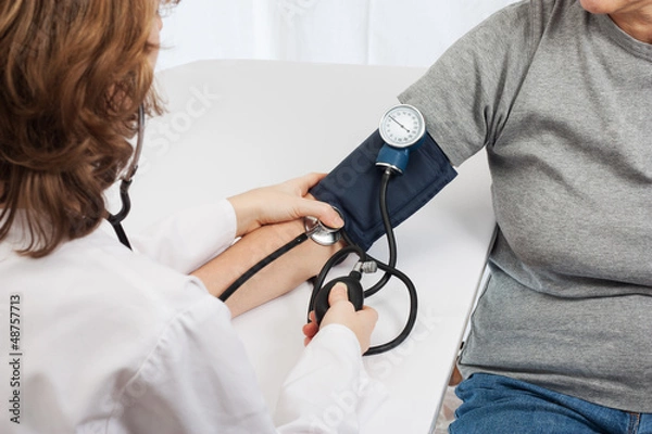 Fototapeta Doctor checking blood pressure with sphygmomanometer