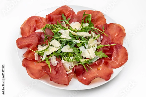 Obraz Plate of bresaola with rocket and parmesan in close-up on a white background. Typical Italian food.