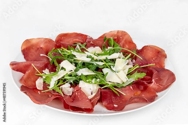 Obraz Plate of bresaola with rocket and parmesan in close-up on a white background. Typical Italian food.