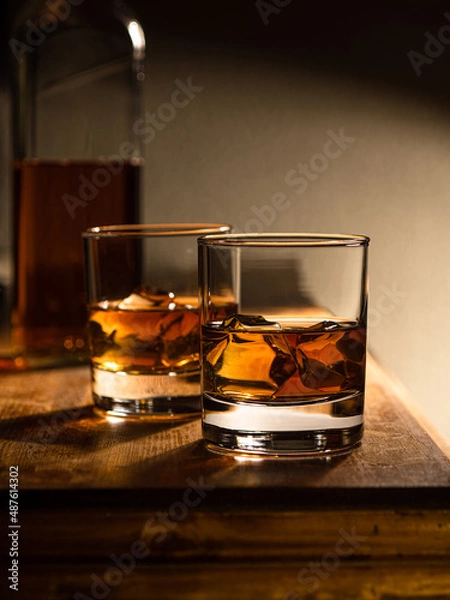 Fototapeta Two glasses of whisky on the rocks on a wooden bartop