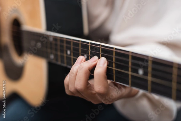 Fototapeta partial view of woman playing acoustic guitar, blurred background.