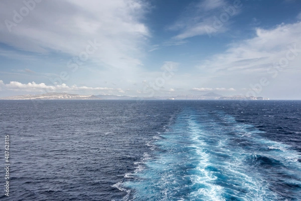 Fototapeta Wake in the Aegean Sea from Cruise Ship. In the background the island of Santorini, Greece