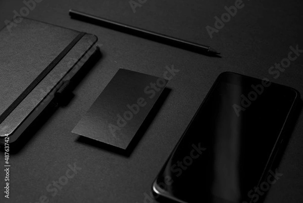 Fototapeta Mock up business template. Black blank business card stationery on black desktop with office supplies