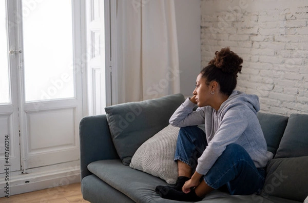 Fototapeta Sad black woman suffering from depression symptoms feeling distressed alone at home