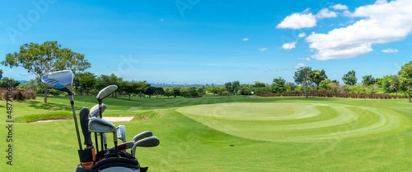 Fototapeta The Golf club bag for golfer training and play in game with golf course background , green tree sun rays.