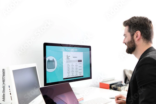 Fototapeta young business man at home working in front of the computer, consulting the sales and the calendar