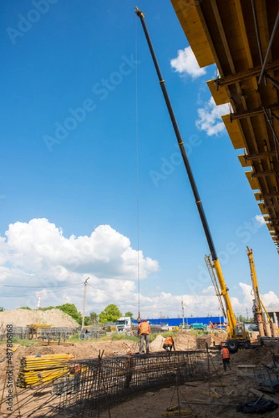 Fototapeta truck crane at a construction site, lifts a metal structure