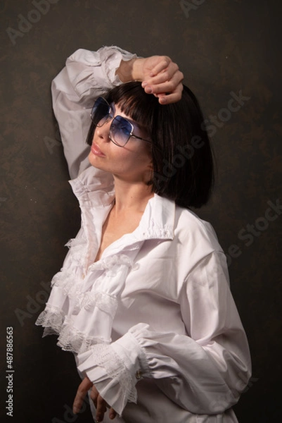 Obraz Young beautiful cheerful girl sitting on floor wearing white blouses and black jeans on the white background. Winter, fall autumn or spring minimal outfit. High quality photo
