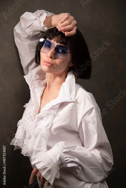 Obraz Young beautiful cheerful girl sitting on floor wearing white blouses and black jeans on the white background. Winter, fall autumn or spring minimal outfit. High quality photo