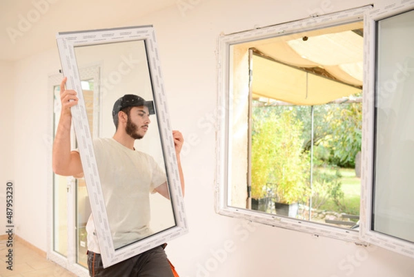 Fototapeta handsome young professional man installing and replacing a new home windows in client house for improvement energy saving efficiency isolation