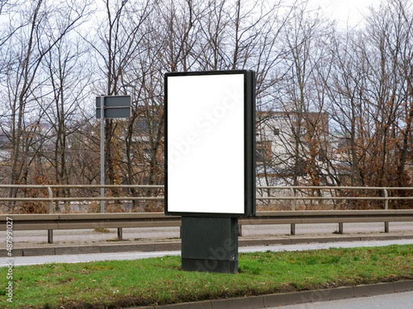 Obraz Blank advertisement screen in the middle of a big street. Mockup of a marketing display in an urban area in the city. Car drivers can see and read the commercial while driving.
