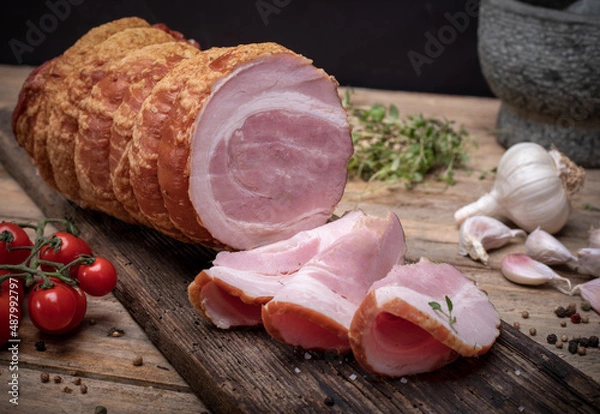 Fototapeta Smoked rolled bacon, pancetta, pork meat roulade, on wooden boards. Composition with Polish cold cuts, meat products.