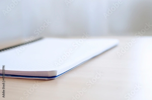 Fototapeta Blurred background with blank notepad on the table. Background for design, advertising, web. Place for text, copyspace.