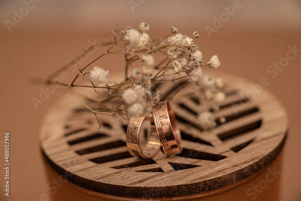 Obraz Wedding ring and dried baby’s breath flowers on beige background.