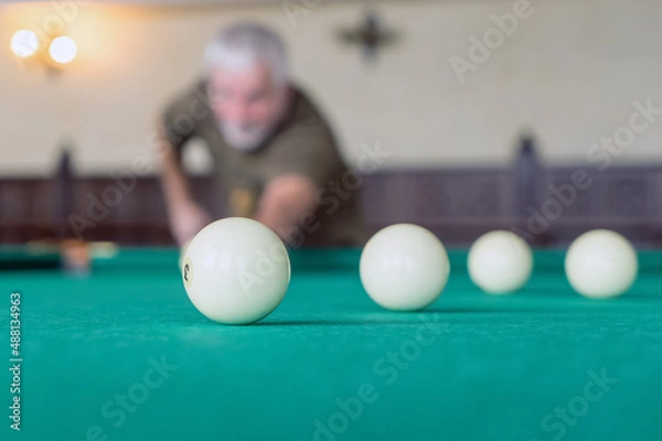 Obraz  An elderly man plays billiards. Selective focus