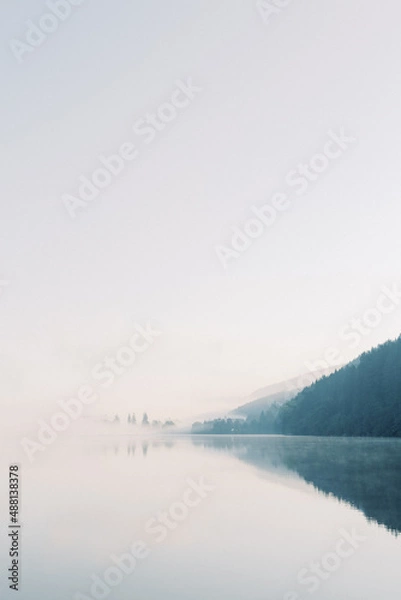 Obraz Lake Titisee Neustadt in Baden-Württemberg in Germany. Blue lake with morning fog with mountains in shadow in the clouds