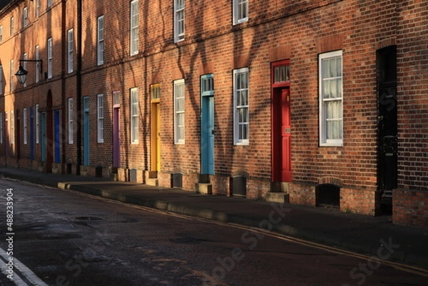 Fototapeta A row of old brick houses with colorful doors