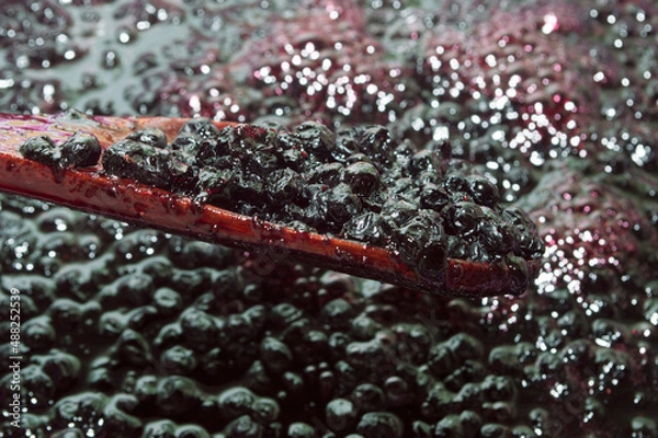 Obraz Blueberries on a wooden spoon. The process of making jam. Harvesting sweet fresh berries for the winter.