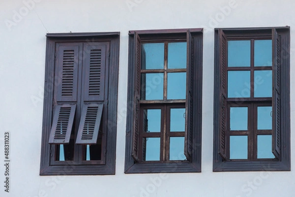 Fototapeta Close-up wall of a stone house with wooden windows and shutters. Old european architecture