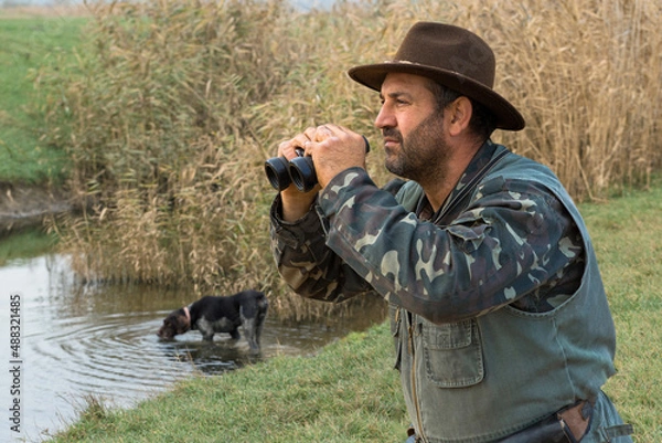 Fototapeta Hunter man in camouflage with a gun during the hunt in search of wild birds or game. Autumn hunting season.