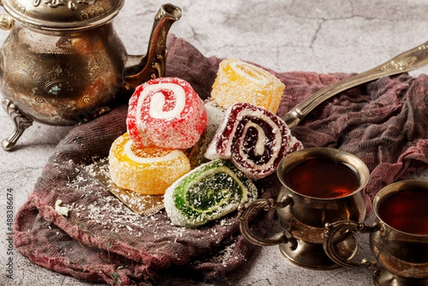 Fototapeta Traditional Turkish delight with Turkish tea on gray background. Ramadan Kareem celebration concept. Fragrant Turkish tea and Turkish sweets in national dishes.