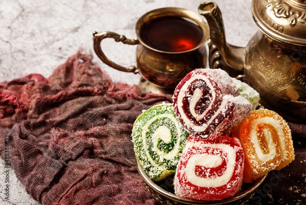 Fototapeta Traditional Turkish delight with Turkish tea on gray background. Ramadan Kareem celebration concept. Fragrant Turkish tea and Turkish sweets in national dishes.