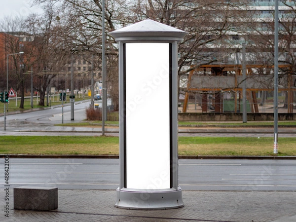 Obraz Advertising column in the city. Blank mockup for testing ad designs on the pillar next to the street. Billboard template with a white rectangle in a city. Copy space in an urban area for marketing.