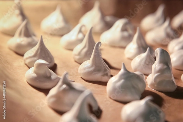Obraz Meringue is baked on a baking sheet covered with parchment paper in the oven close-up