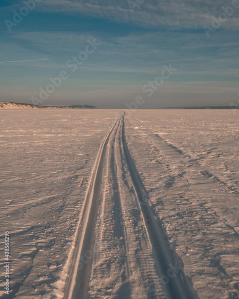 Fototapeta the snowmobile left behind a long strip in the snow	