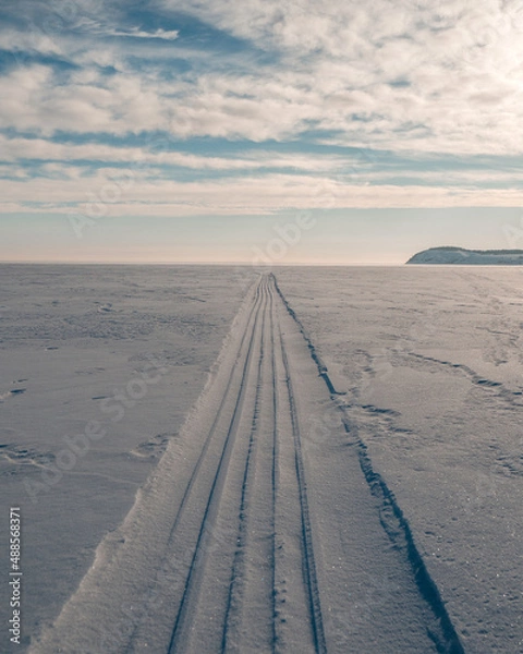 Fototapeta the snowmobile left behind a long strip in the snow	