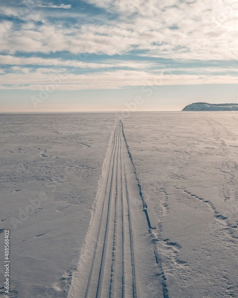 Fototapeta the snowmobile left behind a long strip in the snow	