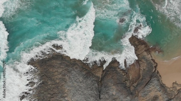 Obraz Crystal green waves crash against the stone coast of
