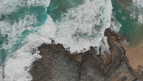 Obraz Crystal green waves crash against the stone coast of