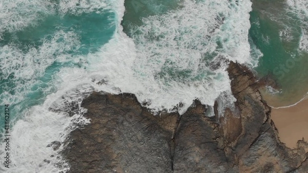 Obraz Crystal green waves crash against the stone coast of