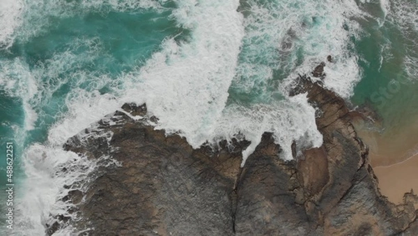 Obraz Crystal green waves crash against the stone coast of