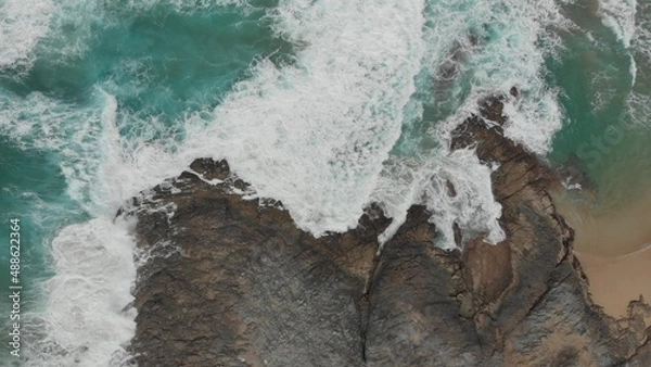 Obraz Crystal green waves crash against the stone coast of