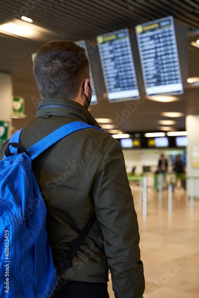Obraz Young man with backpack in airport looking flight timetable