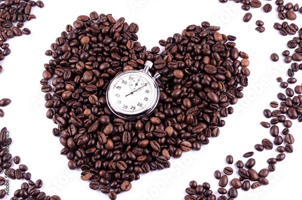 Obraz Coffee beans laid out in the shape of a heart on a white background with a stopwatch, time to drink coffee