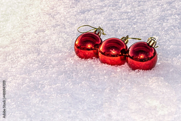 Fototapeta three red christmas tree balls on white snow