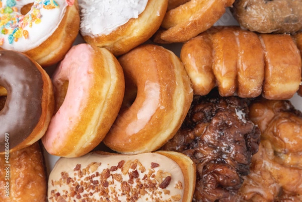 Fototapeta Overhead shot of a box of assorted donuts indoors under studio lighting.