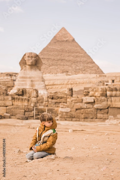 Fototapeta little boy sitting on knees at background of Great Sphinx and Chephren's pyramid in Giza, Egypt