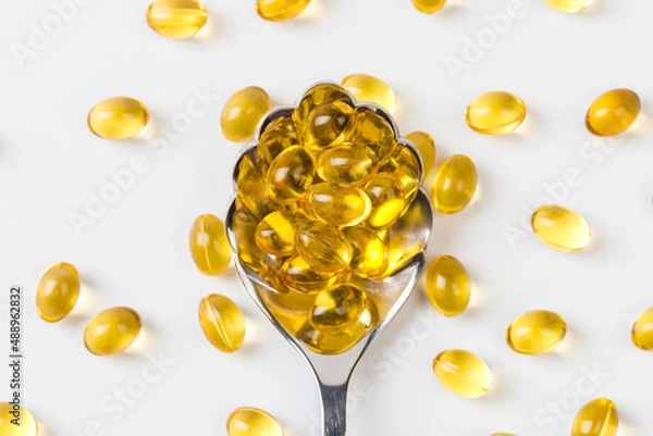 Fototapeta Close up of  oil filled capsules suitable for: fish oil, omega 3, omega 6, omega 9,  vitamin A, vitamin D, vitamin D3, vitamin E with a spoon - Image