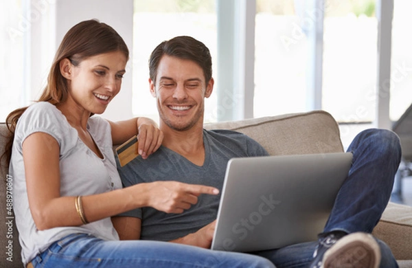 Fototapeta We should totally get that. An affectionate young couple doing some online shopping at home.
