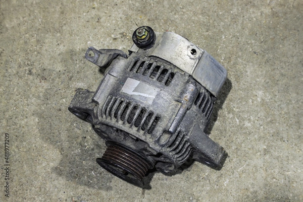 Fototapeta Old dirty car generator on a gray background close-up. Car parts