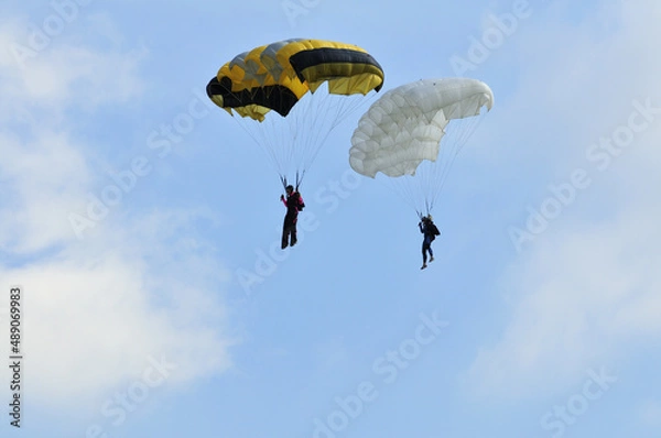 Obraz Athletes skydivers in the blue sky