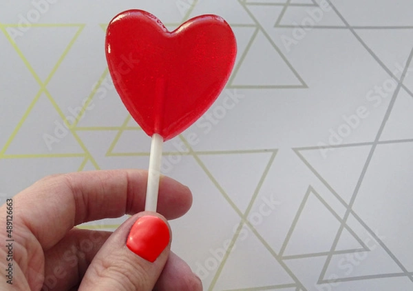 Fototapeta A heart-shaped lollipop in your hand