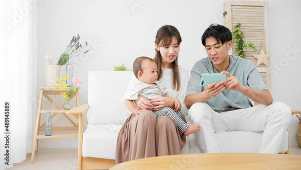 Fototapeta スマートフォンを赤ちゃんに見せる両親