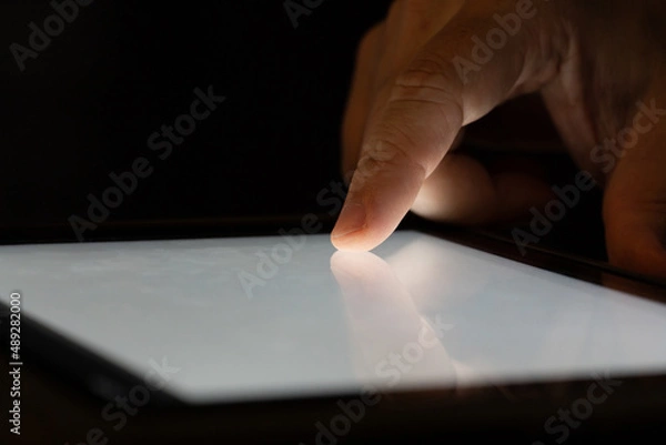 Fototapeta Finger touch on Tablet screen Mock up with light. Concept for mobile phone technology and technology.