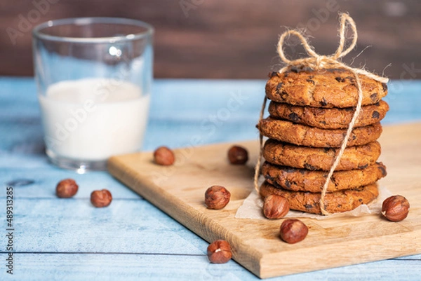 Fototapeta Homemade cookies with raisins, chocolate, nuts and milk on a wooden table and a art phone. Breakfast. Close up.